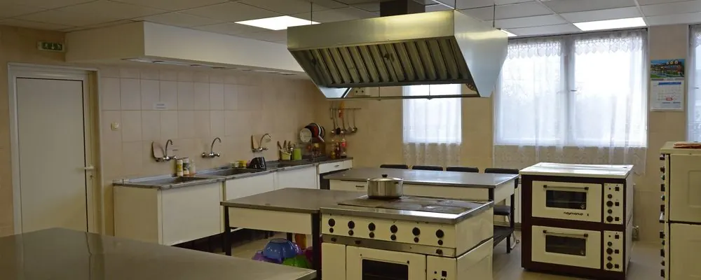 Cuisine collective équipée de plans de travail en inox, d’éviers et de fours : nettoyage des cuisines, offices et zones de repas en crèche
