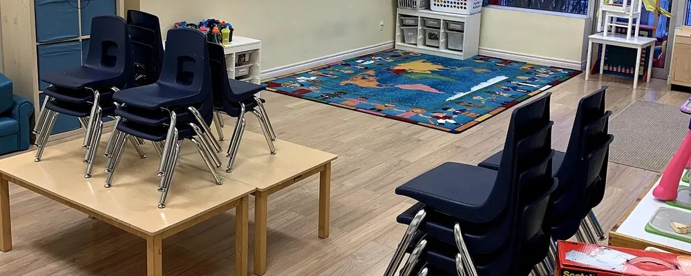 Salle d’activité avec chaises d’enfants empilées sur une table et tapis d’éveil : nettoyage des sols des salles d’activité en crèche