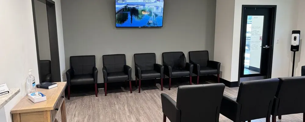 Salle d’attente d’un cabinet médical avec fauteuils noirs et écran : fréquence de nettoyage d’un cabinet médical