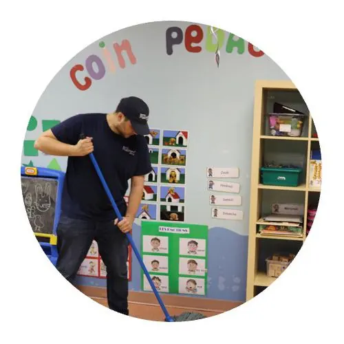 Nettoyage crèches à Paris banlieue par agent avec casquette lavant le sol de la crèche avec un balai